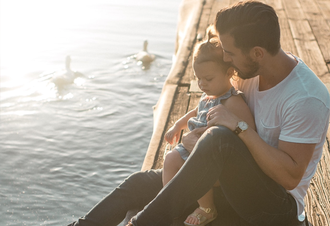 Padre e hija apreciando el lago con patos.